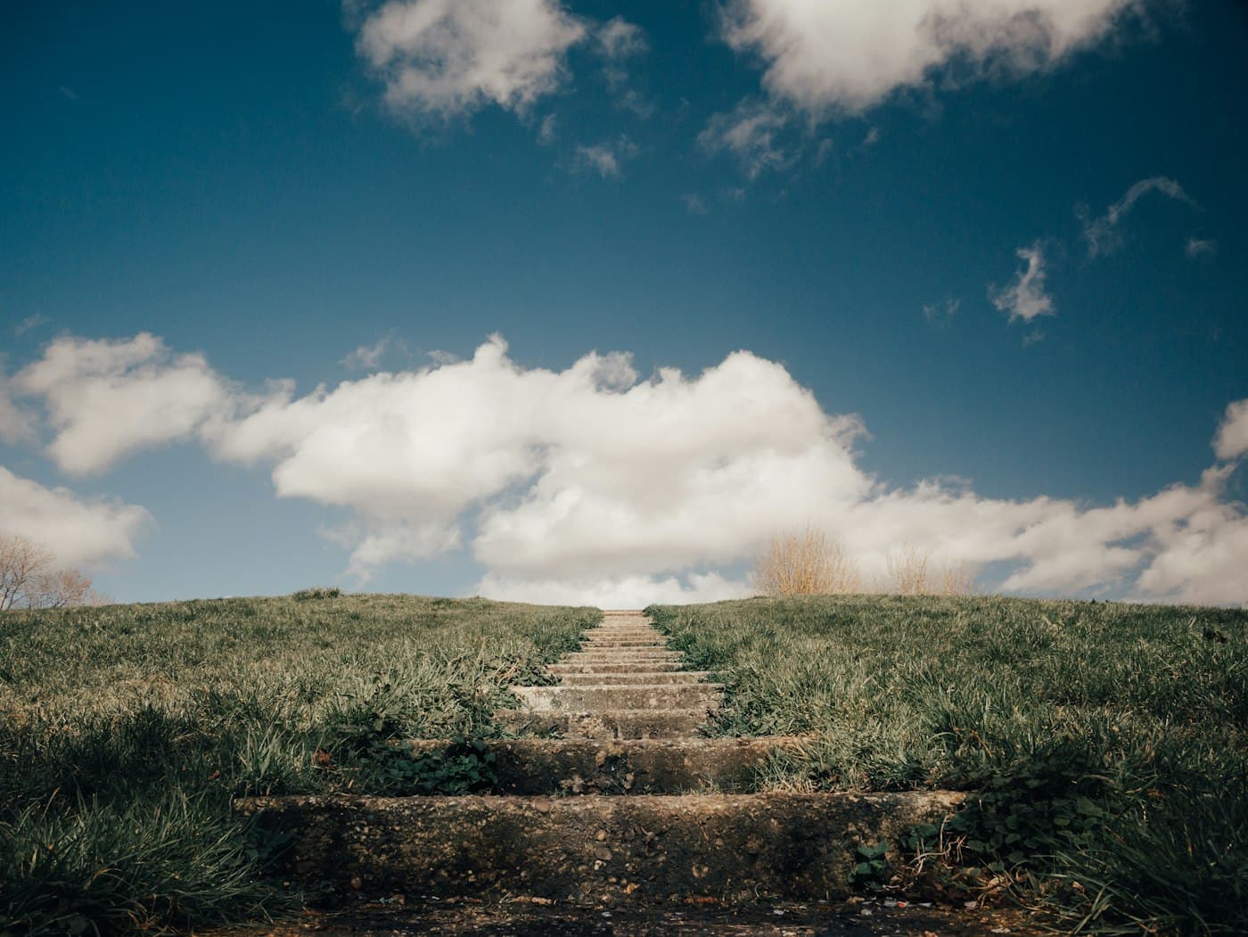 Stairs between grass fields under a blue sky – representing the journey to the cloud.
